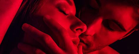 imagem vermelha aproximada de casal com olhos fechados e homem tocando o rosto da mulher