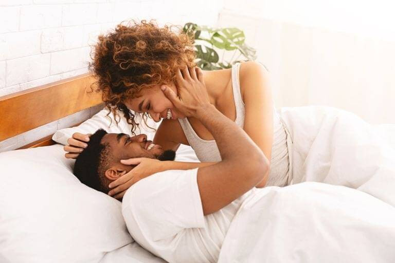 casal de mulher negra e homem negro deitados na cama 